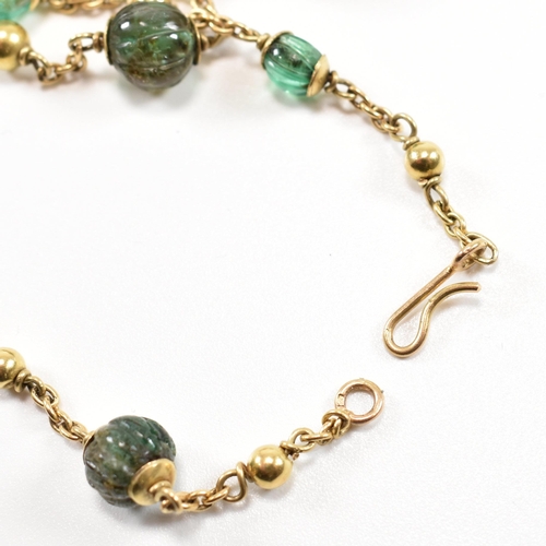 58 - A gold and carved emerald bead necklace. The necklace strung with 15 carved emerald beads having gol... 