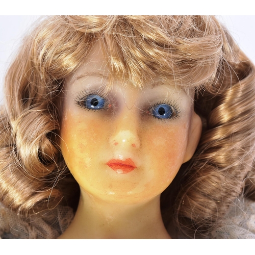 194 - A vintage late 20th Century wax headed doll. Fixed blue eyes, painted lips, cloth body and wax limbs... 