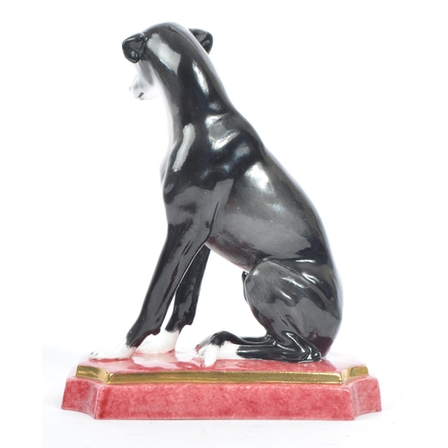 129 - Halcyon Days - A vintage 20th century porcelain figure of a Greyhound dog. In a seat position in a b... 