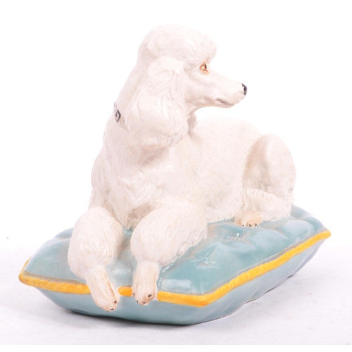 149 - Beswick - A late 20th matte finish white Beswick poodle seated on a blue cushion with yellow trim. M... 