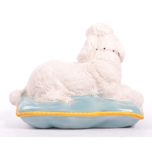 149 - Beswick - A late 20th matte finish white Beswick poodle seated on a blue cushion with yellow trim. M... 