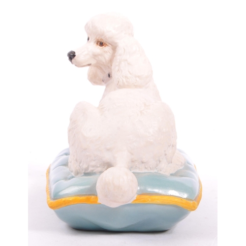 149 - Beswick - A late 20th matte finish white Beswick poodle seated on a blue cushion with yellow trim. M... 