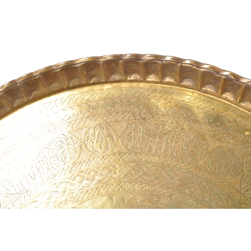 228 - A large 20th century Islamic Middle Eastern engraved brass tray wall charger. The tray having Islami... 