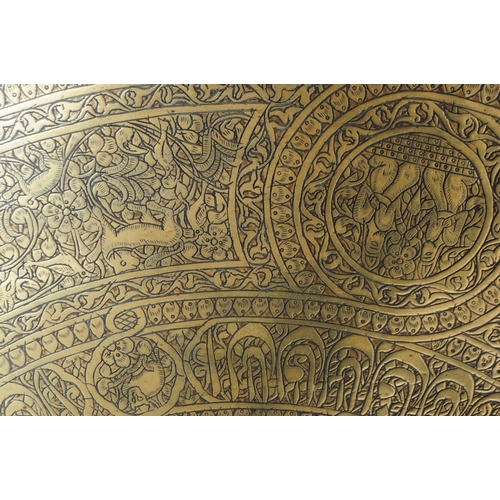 230 - A large 20th century Indian brass engraved wall charger tray. The tray having vignettes of kneeling ... 