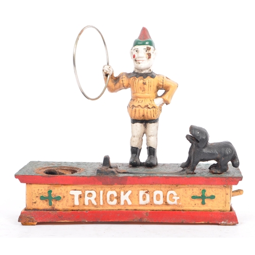 291 - An mid 20th century cast iron 'trick dog' money bank. Having a jester, holding a ring where the dog ... 