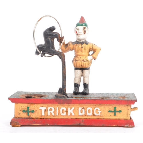 291 - An mid 20th century cast iron 'trick dog' money bank. Having a jester, holding a ring where the dog ... 