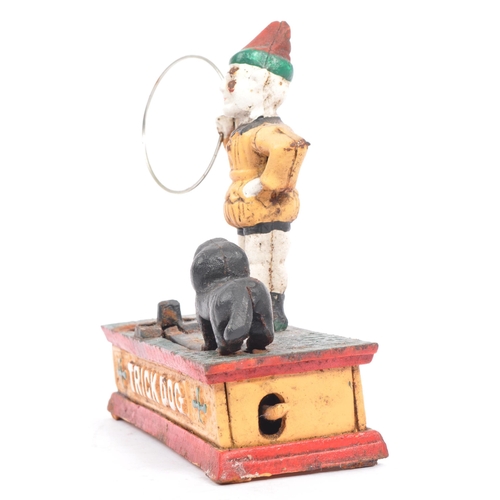 291 - An mid 20th century cast iron 'trick dog' money bank. Having a jester, holding a ring where the dog ... 