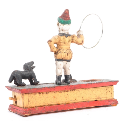 291 - An mid 20th century cast iron 'trick dog' money bank. Having a jester, holding a ring where the dog ... 