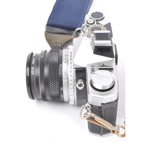 328 - A 20th century circa 1970s Olympus OM-1 MD 35mm SLR camera and lenses. The camera having a metal bod... 