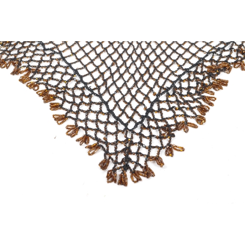 363 - A vintage 1970s art deco style knitted net shawl embellished with orange/brown beads and crochet bor... 