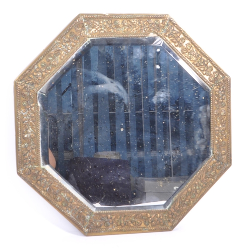 376 - An early 20th century circa 1920s repousse brass wall mirror. The mirror of octagonal form with beve... 