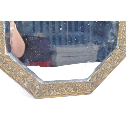 376 - An early 20th century circa 1920s repousse brass wall mirror. The mirror of octagonal form with beve... 