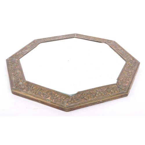 376 - An early 20th century circa 1920s repousse brass wall mirror. The mirror of octagonal form with beve... 