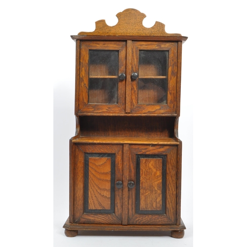 231 - An early 20th century oak apprentice piece Welsh dresser cabinet. With a carved pediment top, into t... 