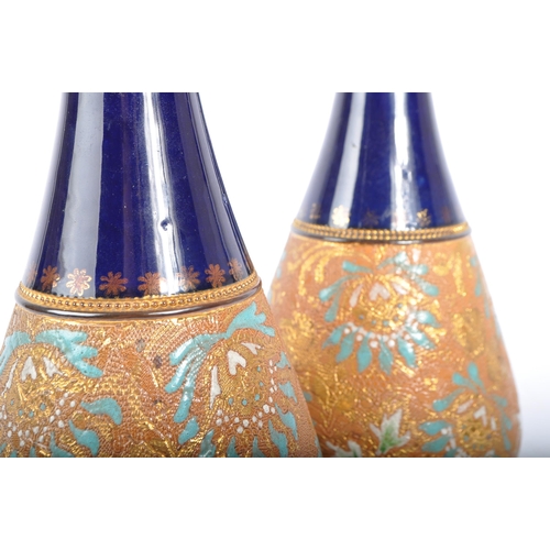 123 - A pair of Royal Doulton Lambeth stem vases. Having a flared blue rim into a tapering neck, with the ... 