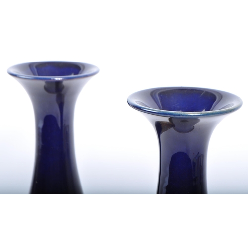 123 - A pair of Royal Doulton Lambeth stem vases. Having a flared blue rim into a tapering neck, with the ... 