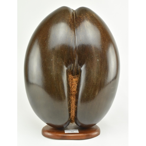 10 - A large polished coco de mer nut. The hollow nut polished and mounted on wood plinth base. Measures ... 