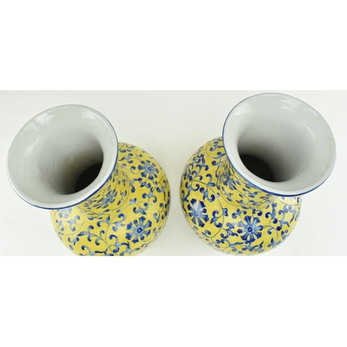 45 - A pair of Chinese Qianlong marked ceramic yellow blue and white glazed vases. Each vase having a fla... 