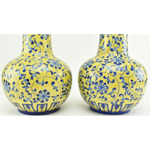 45 - A pair of Chinese Qianlong marked ceramic yellow blue and white glazed vases. Each vase having a fla... 