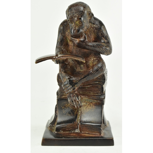 52 - A bronze figure depicting Darwin's reading monkey. The sculpture featuring a monkey reading a book i... 