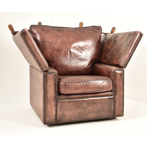 367 - A pair of Knole style brown leather drop-side armchairs. Each armchair having a straight back with w... 