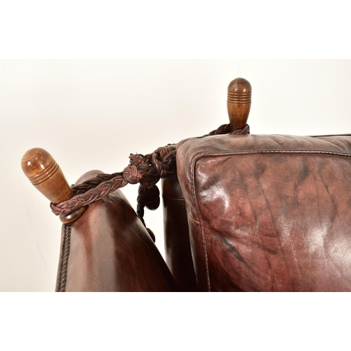 367 - A pair of Knole style brown leather drop-side armchairs. Each armchair having a straight back with w... 