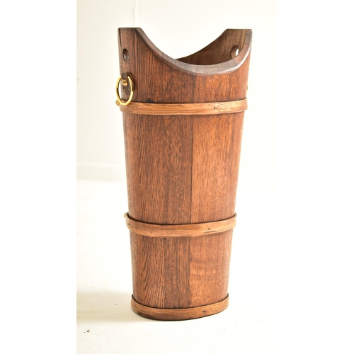 409 - An early 20th century oak staved umbrella / stick stand bucket. The stand having a concave mouth wit... 