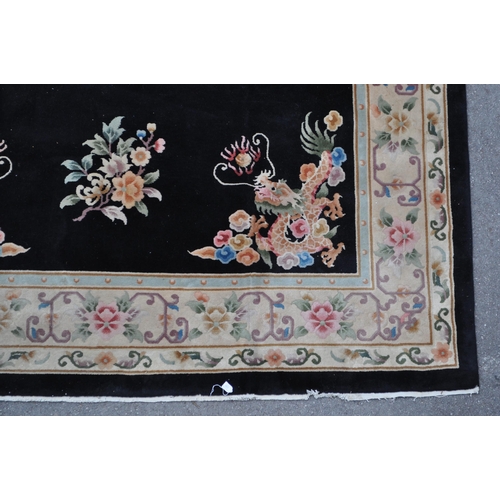 434 - A 20th century Chinese dragon carpet floor rug. With a black ground polychrome circular emblem with ... 