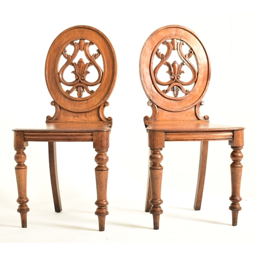 443 - A pair of Victorian 19th century carved oak round back hall chairs. Each chair having a pierced roun... 