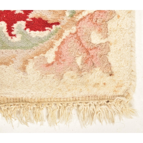 521 - A large 20th century woollen carpet floor rug. The rug of rectangular form with cream ground and red... 