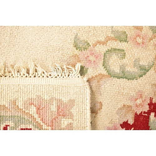 521 - A large 20th century woollen carpet floor rug. The rug of rectangular form with cream ground and red... 