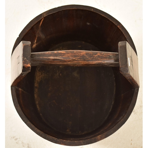 532 - A Chinese inspired hardwood iron bound water bucket. The bucket having a tall wooden straight mortis... 