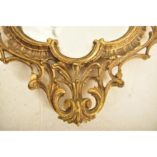 538 - A 19th century continental Baroque inspired gilt metal wall hanging mirror. The mirror having a cart... 