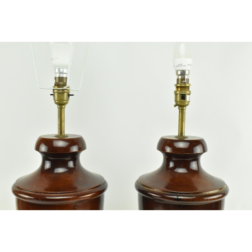 555 - A pair of turned wooden desk table lamps shades in the shape of urn in the manner of Porta Romana. E... 