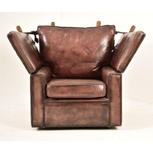 367 - A pair of Knole style brown leather drop-side armchairs. Each armchair having a straight back with w... 