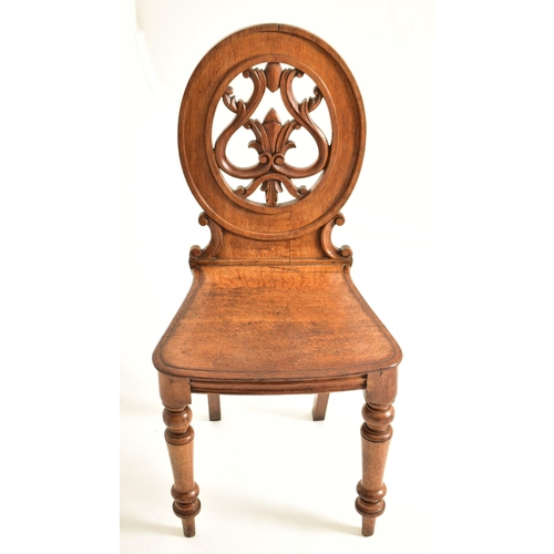 443 - A pair of Victorian 19th century carved oak round back hall chairs. Each chair having a pierced roun... 