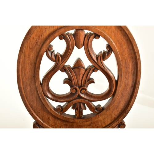 443 - A pair of Victorian 19th century carved oak round back hall chairs. Each chair having a pierced roun... 