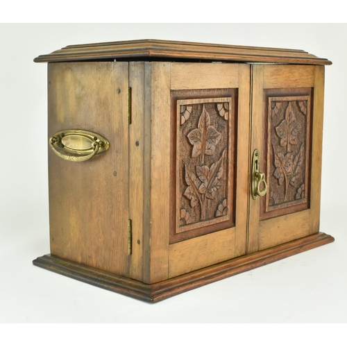 464 - An Edwardian 1912 carved oak smokers / tobacco compendium cabinet. The cabinet having a hinged cover... 