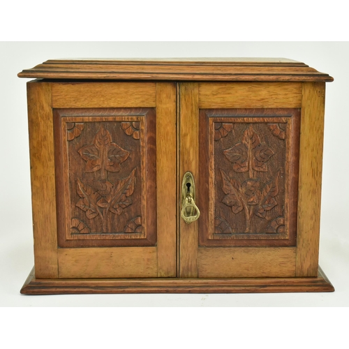 464 - An Edwardian 1912 carved oak smokers / tobacco compendium cabinet. The cabinet having a hinged cover... 