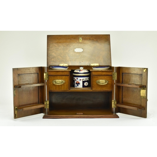 464 - An Edwardian 1912 carved oak smokers / tobacco compendium cabinet. The cabinet having a hinged cover... 