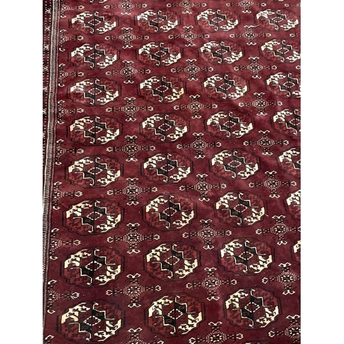 527 - An early 20th century circa 1920s Turkmen Islamic virgin wool floor carpet rug. The rug in burgundy ... 