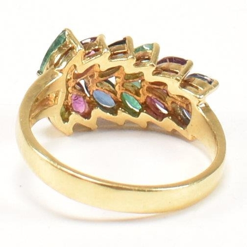 16 - An 18ct gold, emerald, sapphire and ruby cluster ring. The ring having twelve graduating marquis cut... 