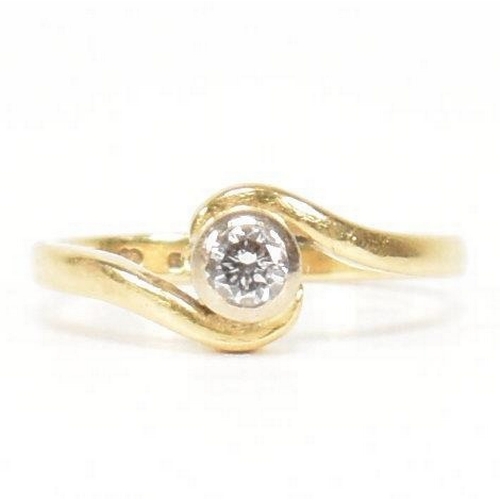 261 - A hallmarked 18ct gold and diamond crossover ring. The ring set with a bezel set central round brill... 