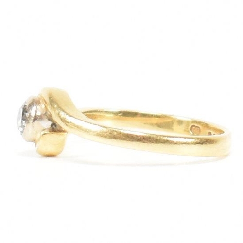 261 - A hallmarked 18ct gold and diamond crossover ring. The ring set with a bezel set central round brill... 