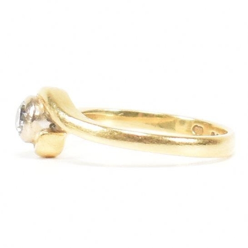 261 - A hallmarked 18ct gold and diamond crossover ring. The ring set with a bezel set central round brill... 