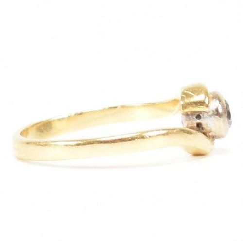 261 - A hallmarked 18ct gold and diamond crossover ring. The ring set with a bezel set central round brill... 