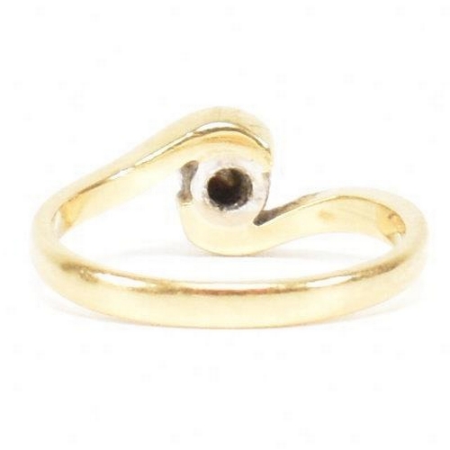 261 - A hallmarked 18ct gold and diamond crossover ring. The ring set with a bezel set central round brill... 