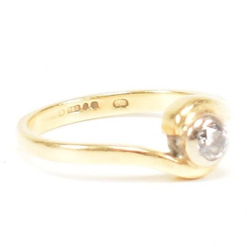 261 - A hallmarked 18ct gold and diamond crossover ring. The ring set with a bezel set central round brill... 