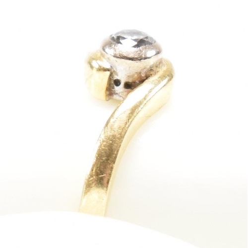 261 - A hallmarked 18ct gold and diamond crossover ring. The ring set with a bezel set central round brill... 