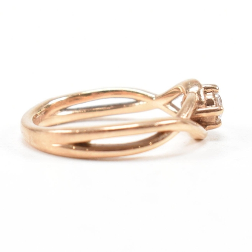 297 - A hallmarked 9ct rose gold and white stone solitaire crossover ring. The single stone engagement sty... 